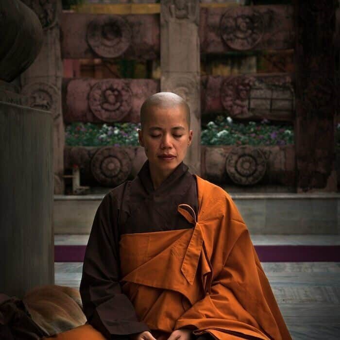 A Buddhist woman meditating on a temple floor