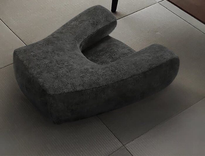 A grey meditation sofa placed on a tiled floor