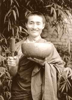 a Tibetan Buddhist monk holding a wooden mallet and a singing bowl - Tibetan singing bowls history