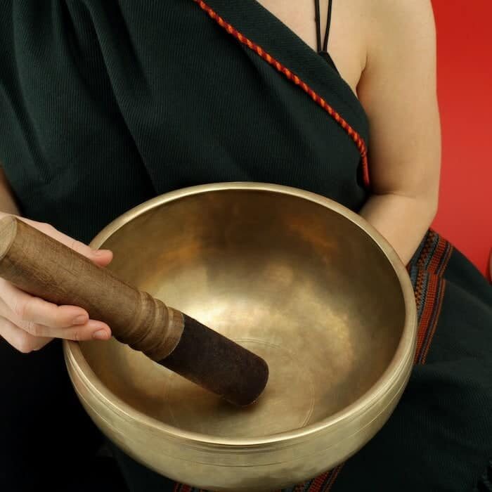 a person holding an antique singing bowls and wooden mallet