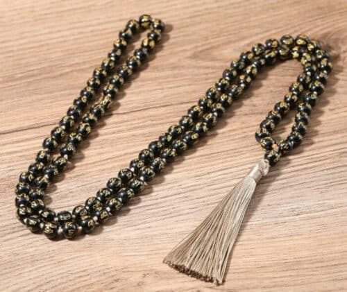 an image of Obsidian Six Words Mantra 108 Beaded Meditation Necklace laying in a wood surface