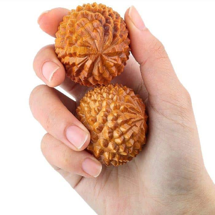 Two spiky wooden meditation balls held in one hand