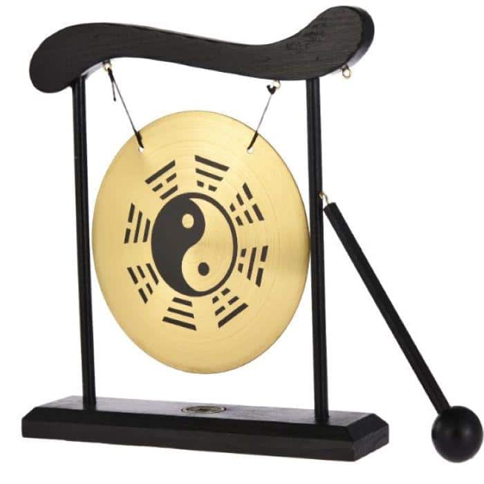 A meditation gong with a Chi design next to a brown mallet