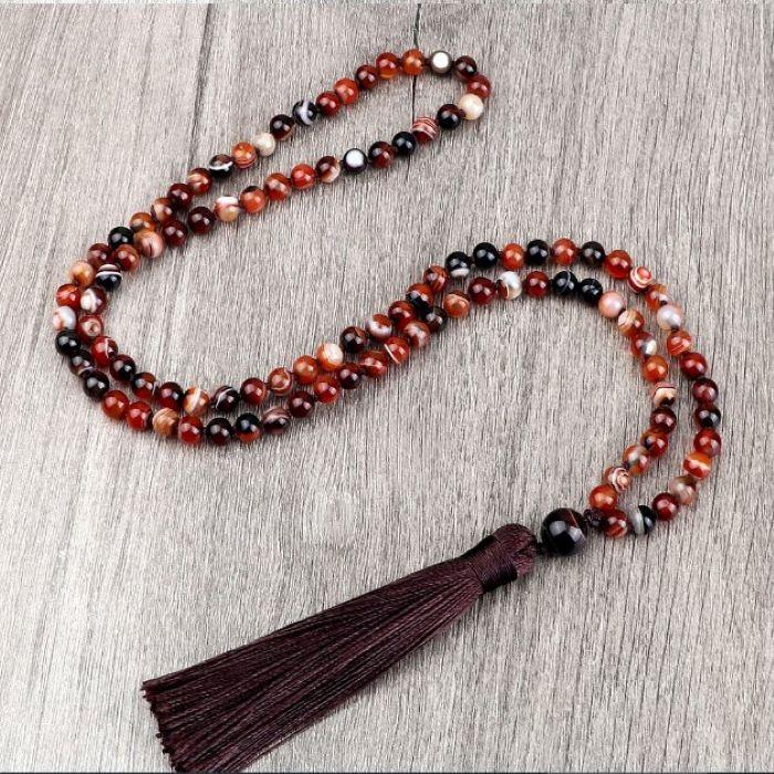 A 108 mala meditation beads with colors of red, white, black, and brown and a red tassel 