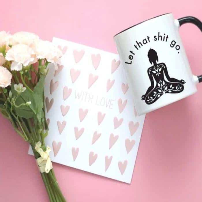 A  white meditation mug with whimsical text next to a letter and flowers
